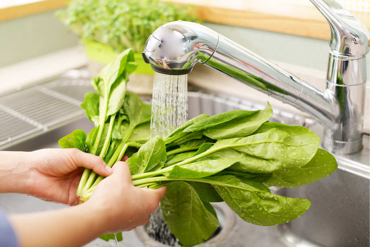 foglie di insalata lavate in cucina sotto l'acqua